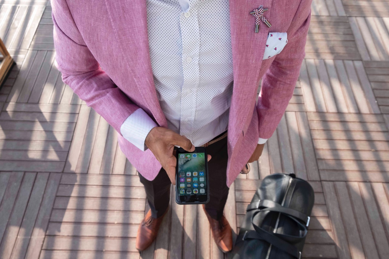 person-standing-beside-duffel-bag-while-using-smartphone-1477955